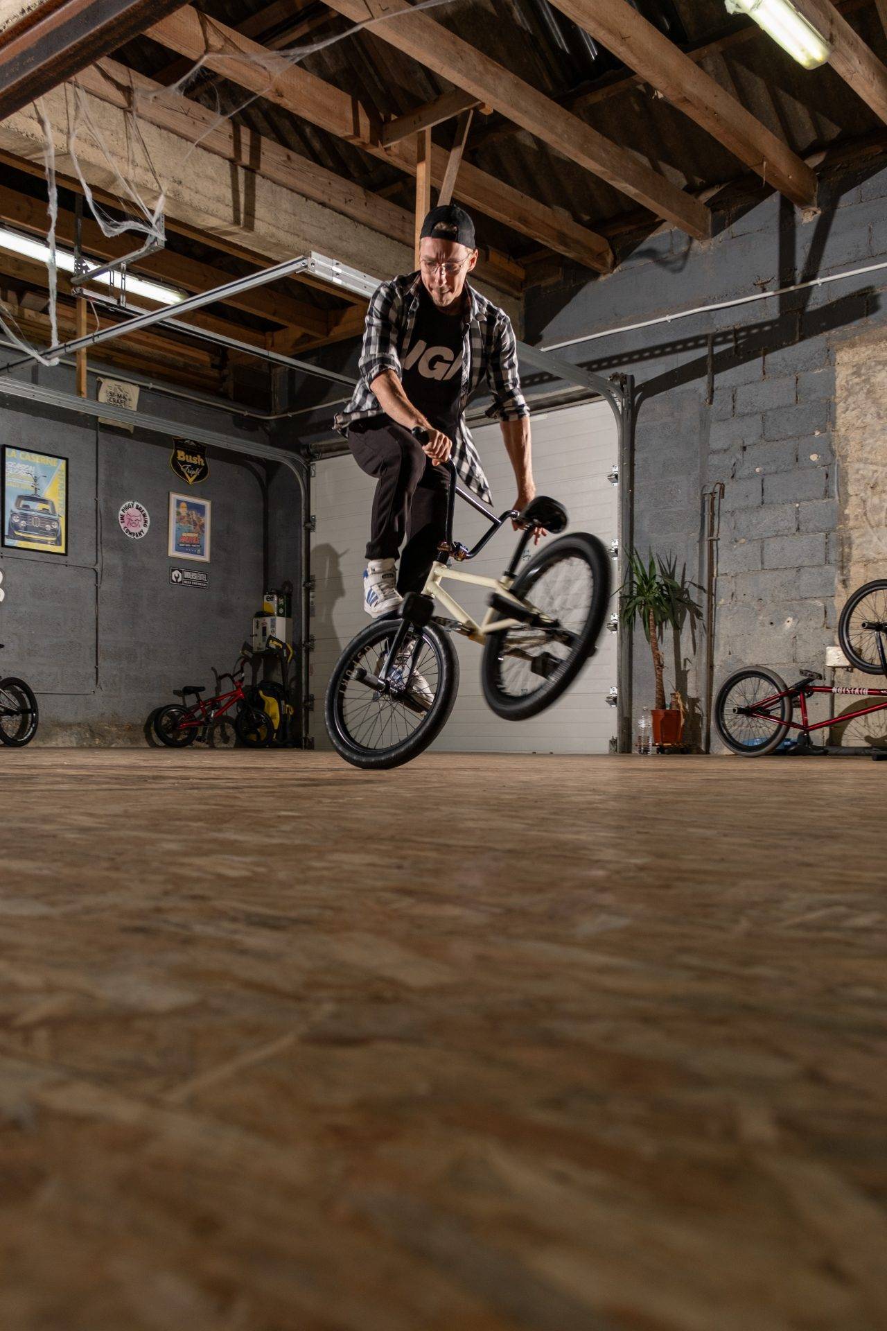 Action de BMX flat en indoor : figure dynamique sur sol OSB